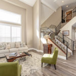 light and bright living room with vaulted ceiling and wrought iron staircase