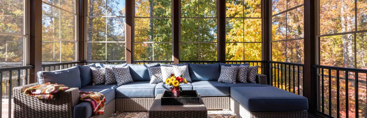 cozy screened porch with couch and fall leaves in the background