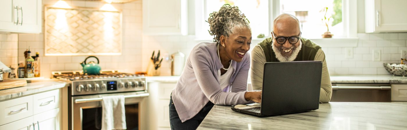couple in kitchen reviewing info on laptop