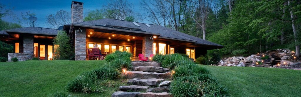 nice home at dusk with lights and gorgeous landscape.