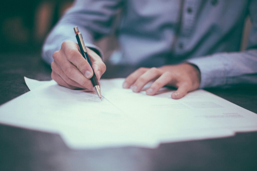 man signing a document with a pen